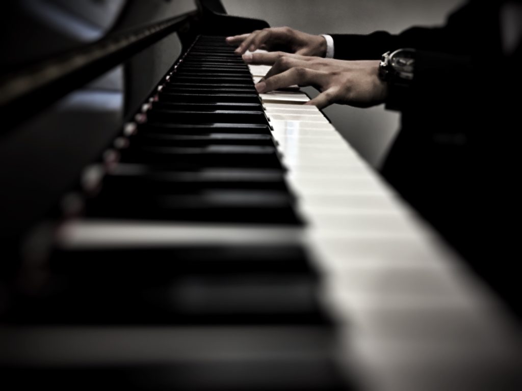 Primer plano de unas manos tocando un piano, capturadas con un enfoque artístico y profundidad de campo.
