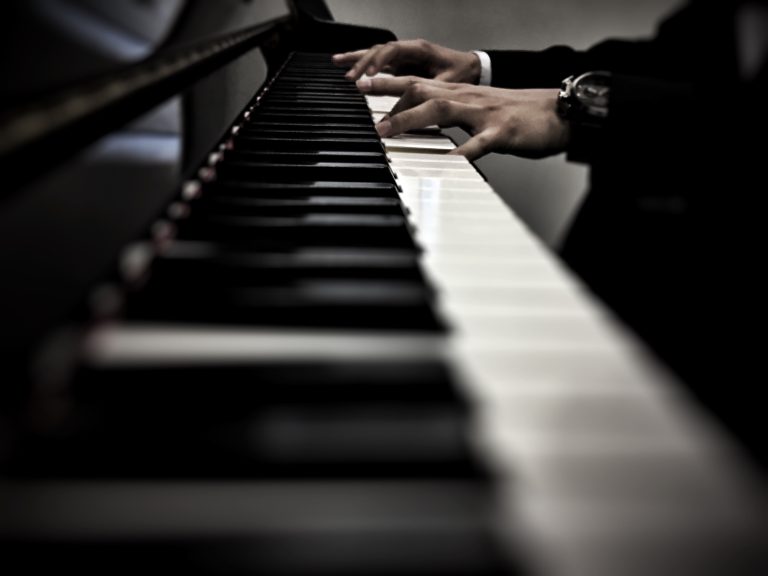 Primer plano de unas manos tocando un piano, capturadas con un enfoque artístico y profundidad de campo.