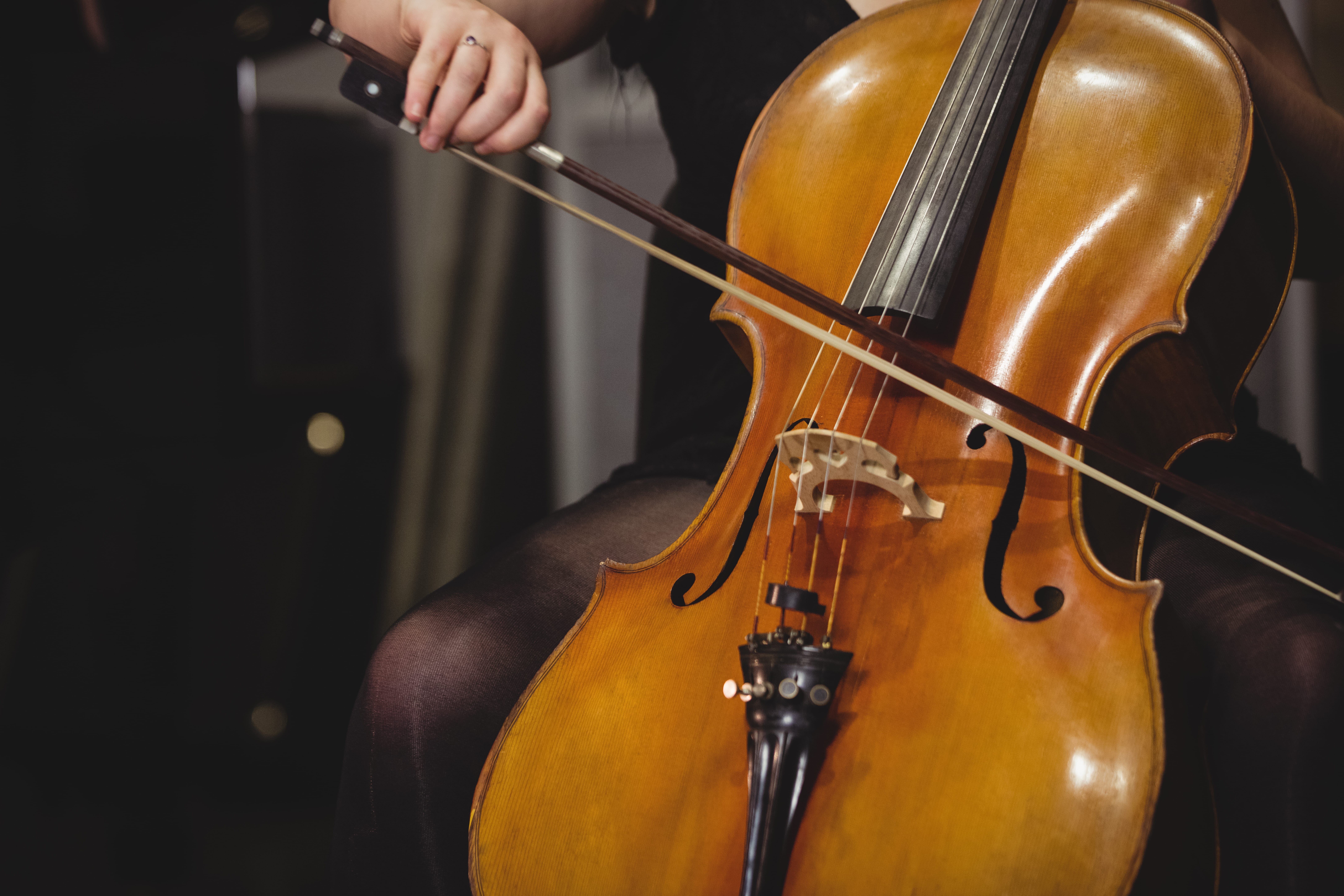 Manos de una persona tocando un violonchelo con arco durante una interpretación musical.